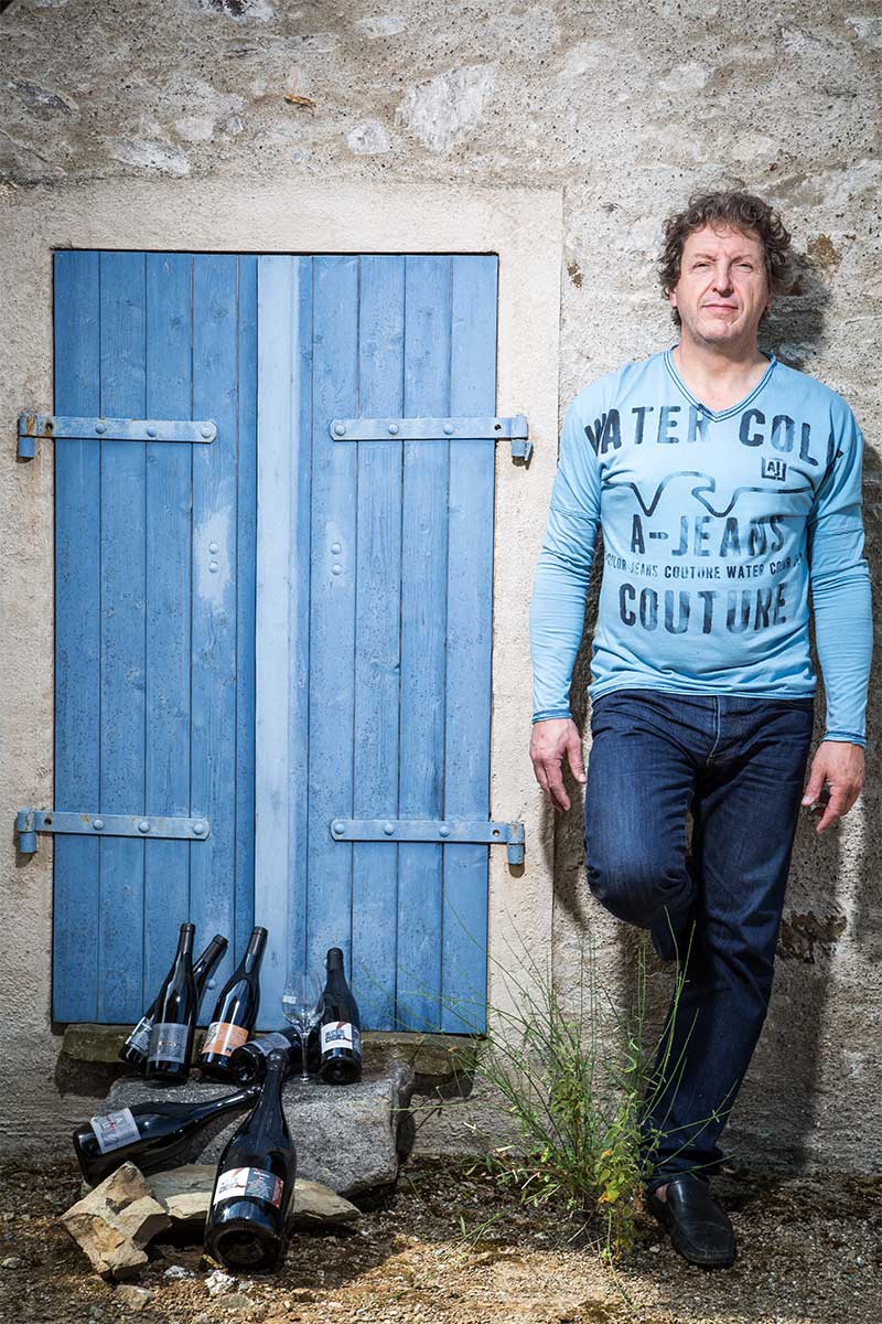Winemaker standing beside blue door with wine bottles at Princess & Bear Wines.