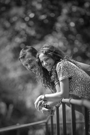 Two young girls leaning on a railing outdoors, enjoying the moment.
